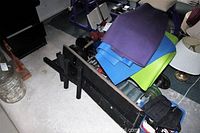 Photo showing black press bench beside rolled yoga mats in purple, blue and green and assorted weights.