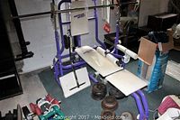 Purple steel frame home gym with white bench and leg curl attachments viewed from front