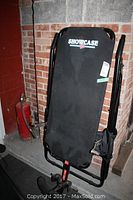 Full view of the folded back inverter exercise equipment showing padded back, steel frame, and handles.
