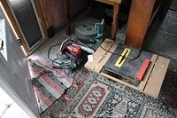 King bench saw with yellow ruler bar, adjacent MK tile saw and Black & Decker manual press on patterned rug.