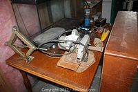 Overall view of the table with the car jack folded, electric hand saw, charger, and other tools.