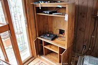 Entertainment shelving unit showing open shelves, side cabinets with doors open, placed beside a glass door.