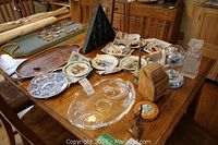 Collector plates, glass decanter, brass incense urn, mantle clock, glass fruit bowl and wooden display stands on wooden table
