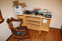 Photo of laminate computer desk with open shelves and pullout tray alongside vintage wooden swivel chair with black cushion