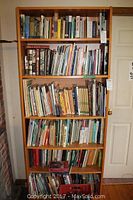 Wooden bookshelf filled with approximately 150 books of various sizes and topics.