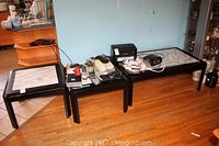 Three wood tables displayed on a wooden floor, showing coffee table and two end tables with marble insets and wear on the painted wood.
