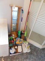 Wide view of wood and glass shelf and assortment of cleaning supplies including mop, bucket, bottles, cloths