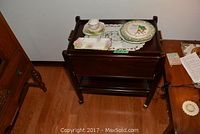 Full view of dark wood serving table with a cup and plate on top, showing overall condition and size.