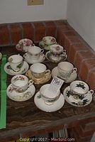 All 10 bone china teacups and saucers on a corner countertop showing a variety of floral and crest patterns.