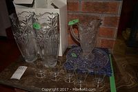 Two tall crystal vases, blue cut glass tray behind, a crystal pitcher and five juice glasses in front.
