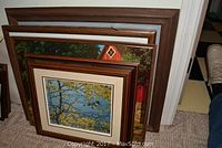 Four framed pictures leaning against wall