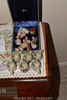 Wade figures and six mini beer steins displayed on a table with lace cloth.