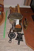 Full lot showing arranged vintage cookware and utensils including metal pot, wooden utensils, rolling pin, trivets, strainer, cake pans, and flat iron.