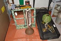 View of brass look lamp, retro ceiling light, Boekamp electric space heater, wooden mirror frame, and retro laundry hamper arranged on floor.