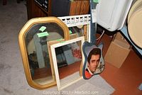 Overview of the guitar-shaped Elvis Presley clock next to three mirrors of varying shape and size on the floor.