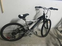 Full view of the mountain bike leaning against a wall showing frame, tires, and seat