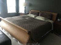 Full view of king size sleigh bed frame showing headboard, footboard, side rails, bedding and adjacent nightstands.