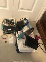 Top view of assorted purses, hand mirrors, and nail polish bottles on carpet.