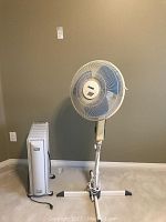 Photo showing Glacier electric fan on adjustable stand next to DeLonghi heater.
