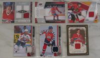 Front view of six hockey cards showing embedded jersey swatches and player images