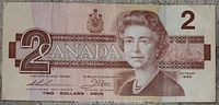 Front side of 1986 Canadian $2 bank note showing Queen Elizabeth II portrait, date, and denomination.