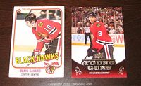 Front of Denis Savard O-Pee-Chee rookie card and Nick Leddy Upper Deck Young Guns hockey card together on a wooden surface.