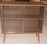 Front view of the wooden display cabinet showing sliding glass doors and interior shelf.