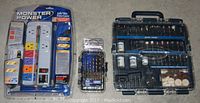 Three unopened items photographed from above: a Monster Power Audio Video Power Center in retail packaging, Mastercraft 13-piece tap and drill set in plastic case, and Mastercraft 170-piece general purpose accessory kit in larger plastic case with visible tools and components.