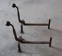 Side view of the pair of hand-forged iron andirons showing curved backplates and claw feet