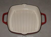 Top view of the square red enameled cast iron Dutch oven showing ribbed cream-colored interior and two handles.