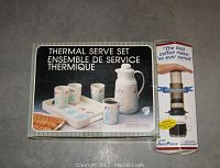 Photo of the boxed Thermal Serve Set with four matching cups and tray, alongside boxed AeroPress Coffee Maker.