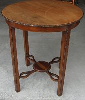 Full view of the round wooden table showing the tabletop, legs, and stretcher base with decorative carvings.