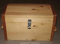 Closed wooden chest showing front, metal latch and reddish wood corner trims under linseed oil finish.
