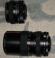 Two Makinon camera lenses displayed side by side showing their relative sizes and detailed aperture and focus markings.