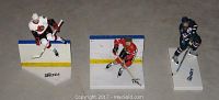 Three NHL hockey player figures lined up side by side on a grey surface, each on a base with player names visible: Hemsky, Orr and Spezza. The figures are detailed plastic representations, each approximately 6 inches tall, showing players in skating poses with hockey sticks.