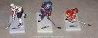 Three hockey player figures displayed side by side: Ovechkin in white Capitals uniform, Gretsky in blue Oilers uniform, and Gilmour in red Flames uniform, each mounted on a white base with their names.