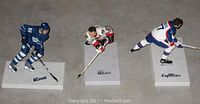 Three hockey player figurines displayed on white rectangular bases with brand names Blake, Makita, and Esposito, showing uniform colors and action poses.