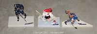 Photo of three hockey figurines: Pronger, Luongo, and Messier, each on white bases with their names labeled, showing detail and colors of the figures.