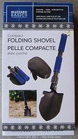 Front packaging showing shovel with blue handle, folding shovel blade with saw edge, bottle opener attachment, and black pouch.