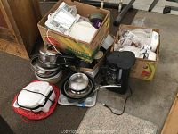 Overview photo showing all kitchen items including boxed casseroles, pots, pans, coffee maker and grill on floor