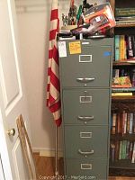 Sears 4-drawer metal file cabinet next to an American flag with pole, showing tools on top of the cabinet.