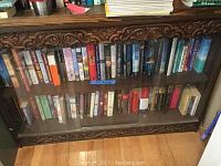 Full view of bottom part of book shelf with glass doors and two shelves filled with books.