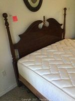 Full view of Queen Ann wooden headboard with ornate turned posts and finials, mattress, and part of box spring beneath mattress visible.
