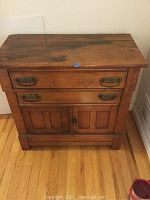 Front view of vintage wooden storage cabinet with two drawers and double doors at the bottom.