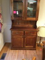Full view of wooden two-piece china cabinet showing bottom section with drawers and doors.