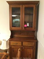 Front view of the full two-piece wooden china cabinet showing upper glass doors, lower drawers and cupboard doors.