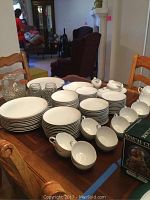 Full display of Harmony House Fine China set including plates, bowls, cups, saucers, serving pieces, glass pitcher and glasses arranged on a wooden dining table.