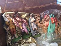 Nativity scene figurines including shepherds and camel with detailed paint and resin material inside box with cloth lining.