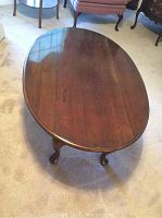 Oval brown wooden table with both leaves down, showing overall shape and wood surface condition.