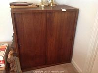 Wooden bookcase with sliding doors shown, medium-dark wood, closed doors